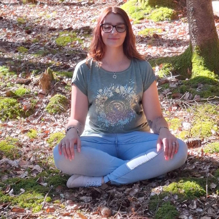 Stefanie sitzt im Wald auf dem Moos